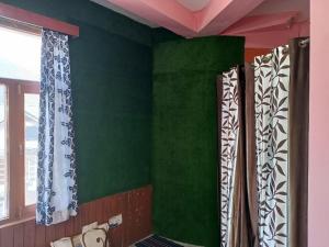 马拉里ROOP MOUNTAIN HOMESTAY的绿色墙壁和带窗帘的窗户。