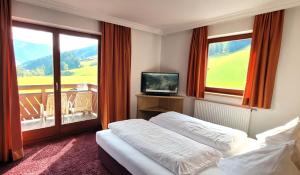 萨尔巴赫Hotel Sommerer - inklusive JOKER CARD im Sommer的一间卧室配有一张床、一台电视和一个阳台