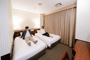 大阪西乐雷斯酒店的两人坐在酒店房间的床边