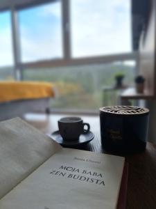 迪瓦伊巴雷Divchy dream studio的坐在书旁边的桌子上喝杯咖啡