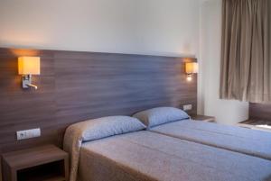帕尔马海滩Cabot Tres Torres Apartamentos的卧室配有一张床,墙上有两盏灯