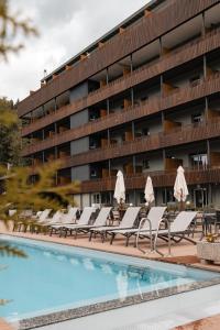 克莱恩 蒙塔纳Faern Crans-Montana Valaisia的酒店游泳池设有躺椅,酒店大楼