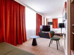 里昂里昂诺福特融合酒店的酒店客房设有床、桌子和电视。