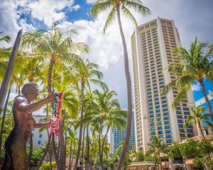 檀香山威基基海滩凯悦水疗度假酒店的棕榈树和建筑前的雕像