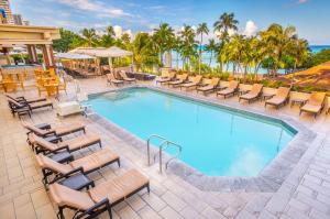 檀香山威基基海滩凯悦水疗度假酒店的一个带躺椅和桌子的大型游泳池