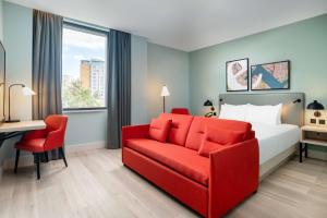 伦敦Hyatt Place London City East的酒店客房,配有一张床和一张红色的沙发