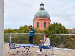 图卢兹Aparthotel Adagio Original Toulouse Centre La Grave的两人坐在阳台,后方是一座建筑