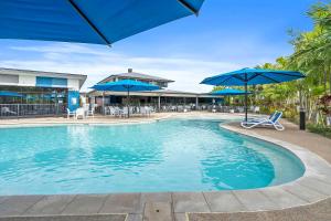 洛坎普顿Quality Resort Parkhurst的一个带蓝伞、椅子和桌子的游泳池