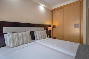 阿尔布费拉Areias Village Beach Suite Hotel的卧室配有一张带两个枕头的大白色床