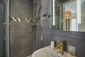 巴黎巴黎北站梅尔里勒酒店的浴室配有盥洗盆和带镜子的淋浴