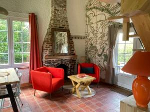 梅斯尼圣佩尔Les Cottages d'Orient Premium的客厅配有红色椅子和壁炉