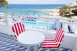 圣埃乌拉利亚Hotel Mongibello Ibiza的海滩阳台配有两把椅子和一张桌子