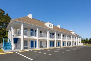 布伦瑞克贝蒙特套房酒店的一座白色的大建筑,设有蓝色的门和停车场