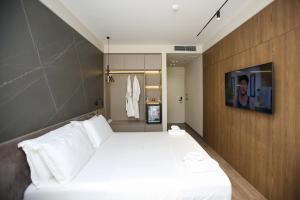 伏罗拉Charm Hotel的卧室配有一张白色大床和电视。