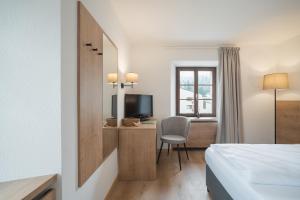 圣贝纳迪诺Hotel Brocco & Posta的酒店客房配有一张床、一张桌子和一把椅子。