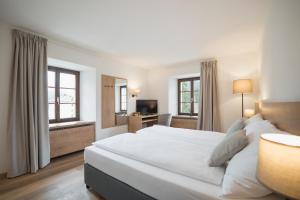 圣贝纳迪诺Hotel Brocco & Posta的卧室设有一张白色大床和两个窗户。
