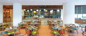 吉隆坡Hilton Garden Inn Kuala Lumpur - South的一间带桌椅的餐厅和一间酒吧
