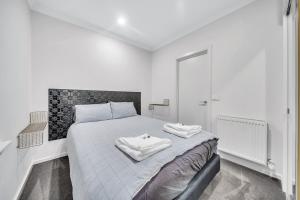 墨尔本Grosvenor 3121 Richmond的白色卧室配有带2条毛巾的床