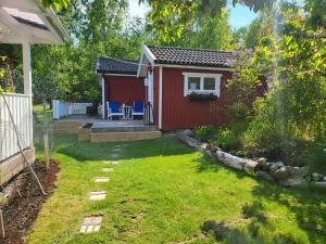 特鲁萨Minihus med stor trädgårdstomt nära golf och hav的一座红色的小房子,有院子