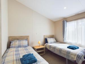 赖德E7 Roebeck Country park的带窗户的客房内设有两张单人床。