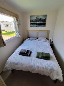 塞顿港G & M Static Caravan Edinburgh的一间卧室配有一张床,上面有两条毛巾