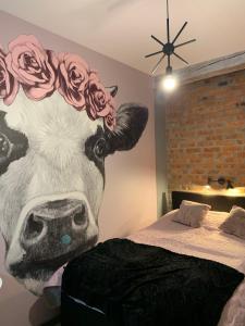 OstrówSiedlisko Kępina Zdrój的一张挂在床上的牛的壁画,头上有玫瑰花