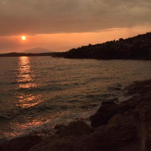 萨拉米斯Salamis Beachfront House的日落在水体上,日落在太阳下