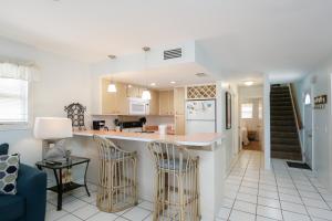 Cape San BlasWhataday by Pristine Properties Vacation Rentals的厨房以及带柜台和椅子的客厅。
