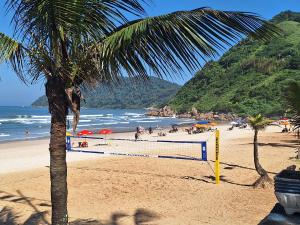 瓜鲁雅Duplex pé na areia, praia do Tombo - Guarujá/SP.的海滩上有人种着棕榈树