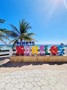 坎昆Home's Jungle Puerto Morelos Cancun 20 Minutes from the Airport的海滩上的标志,背后是棕榈树