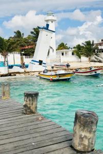 坎昆Home's Jungle Puerto Morelos Cancun 20 Minutes from the Airport的灯塔旁边的水面上的船