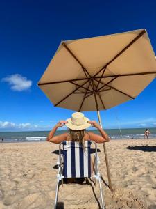 若昂佩索阿Kastel Jampa Hotel的坐在海滩上一把伞下的椅子上的女人