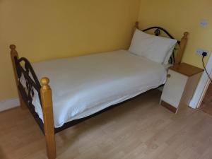 科克Sheraton Lodge Apartments t12e309的一张带木架和白色床单的床和一个床头柜