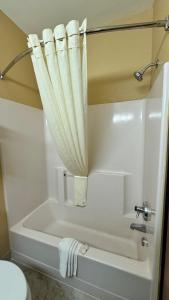 欧克莱尔套房品质酒店的浴室内设有带浴帘的白色浴缸