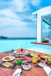 米克诺斯城Gorgeous Villa BR Suite Astonishing Sea View的一张桌子,上面摆放着食品和饮料,并享有海景