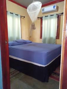 Santa RitaJungle Vacation Home with river and waterfall.的一间卧室配有一张带蓝色床单和窗帘的床