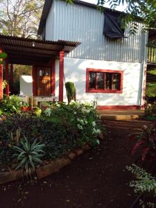 Santa RitaJungle Vacation Home with river and waterfall.的一间白色的小房子,设有红色窗户