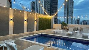 巴拿马城Victoria Hotel and Suites Panama的一个带游泳池和桌椅的屋顶露台