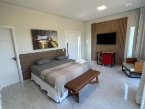 博阿维斯塔Villa'S Roraima - Pousada & Natureza的一间卧室配有一张床、一张桌子和一台电视。