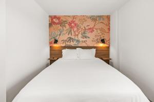圣地亚哥Uptown Inn by Vantaggio Suites的卧室配有白色的床和花卉壁纸