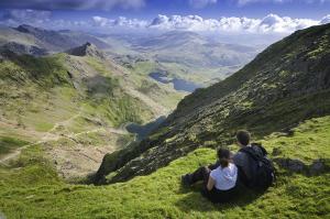 多尔盖罗Y Meirionnydd Townhouse的两个人坐在山上,望着山谷