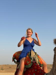 斋沙默尔Best Desert Camp In Jaisalmer Red Velvet的穿着蓝色衣服的女人坐在骆驼上