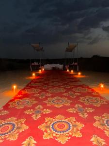 斋沙默尔Best Desert Camp In Jaisalmer Red Velvet的沙滩上长长的红地毯和蜡烛