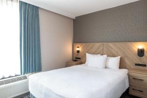 温哥华戴维桑德曼套房酒店的卧室设有一张白色大床和一扇窗户。