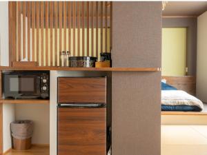 野沢长野野沢日式旅馆的带冰箱的厨房和客房内的一张床