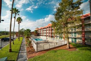 奥兰多Developer Inn Downtown Orlando, a Baymont by Wyndham的公寓大楼设有游泳池和棕榈树