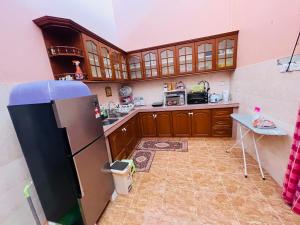 哥打巴鲁Kota Bharu Homestay的厨房配有木制橱柜和冰箱。