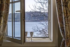 特拉凯阿尔戈特拉凯酒店的两杯玻璃坐在窗台上,望着水面