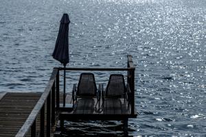 特拉凯阿尔戈特拉凯酒店的码头上的两把椅子,上面有雨伞和水
