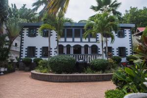 拉迪格岛圣云城堡酒店的一座白色的建筑,前面有棕榈树